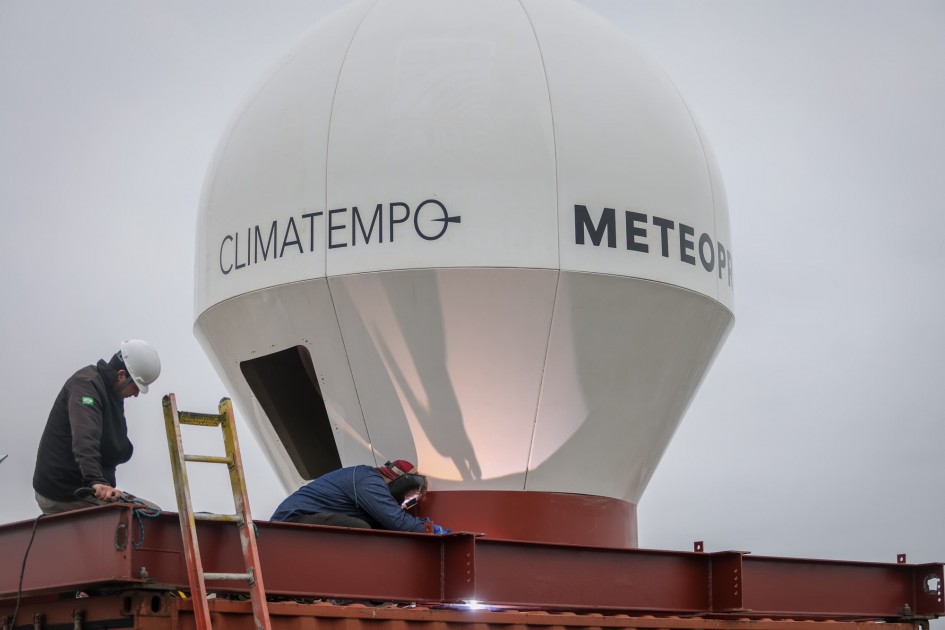 O novo radar meteorológico do Rio Grande do Sul deve entrar em funcionamento em breve. O equipamento já foi instalado no Morro da Polícia, em Porto Alegre – onde, a princípio, funcionará provisoriamente – e passará por ajustes e testes para que possa começar a operar. A Climatempo, empresa que venceu a licitação para fornecer o serviço de monitoramento de condições meteorológicas para o Estado, adquiriu e operará o equipamento. Segundo a Defesa Civil, a partir desta quinta-feira (8/8), o radar será ligado às redes de energia e de internet. Durante a próxima semana, técnicos da Meteopress, fabricante do equipamento, trabalharão em configurações e testes dos componentes eletrônicos. Simultaneamente, equipes da mesma empresa calibrarão o equipamento com a instalação de softwares da Climatempo e também farão outras ações necessárias para que a Sala de Situação do Estado comece a receber os primeiros dados gerados. O radar utiliza uma tecnologia chamada nowcasting, que permite a coleta de dados meteorológicos em tempo real, possibilitando à Defesa Civil emitir alertas e relatórios mais precisos. De acordo com a meteorologista Cátia Valente, da Sala de Situação, o equipamento tem um alcance de cerca de 150 quilômetros e conta com um software embutido que transforma os dados captados em imagens das condições atmosféricas. “O radar utiliza tecnologia de ponta. Os dados brutos são processados para gerar imagens que mostram, entre outras informações, volume de chuvas e granizo, além de velocidade e direção dos ventos. Isso vai propiciar uma previsão do tempo bem mais acurada, melhorando significativamente a assertividade dos alertas emitidos à população”, explica Cátia.